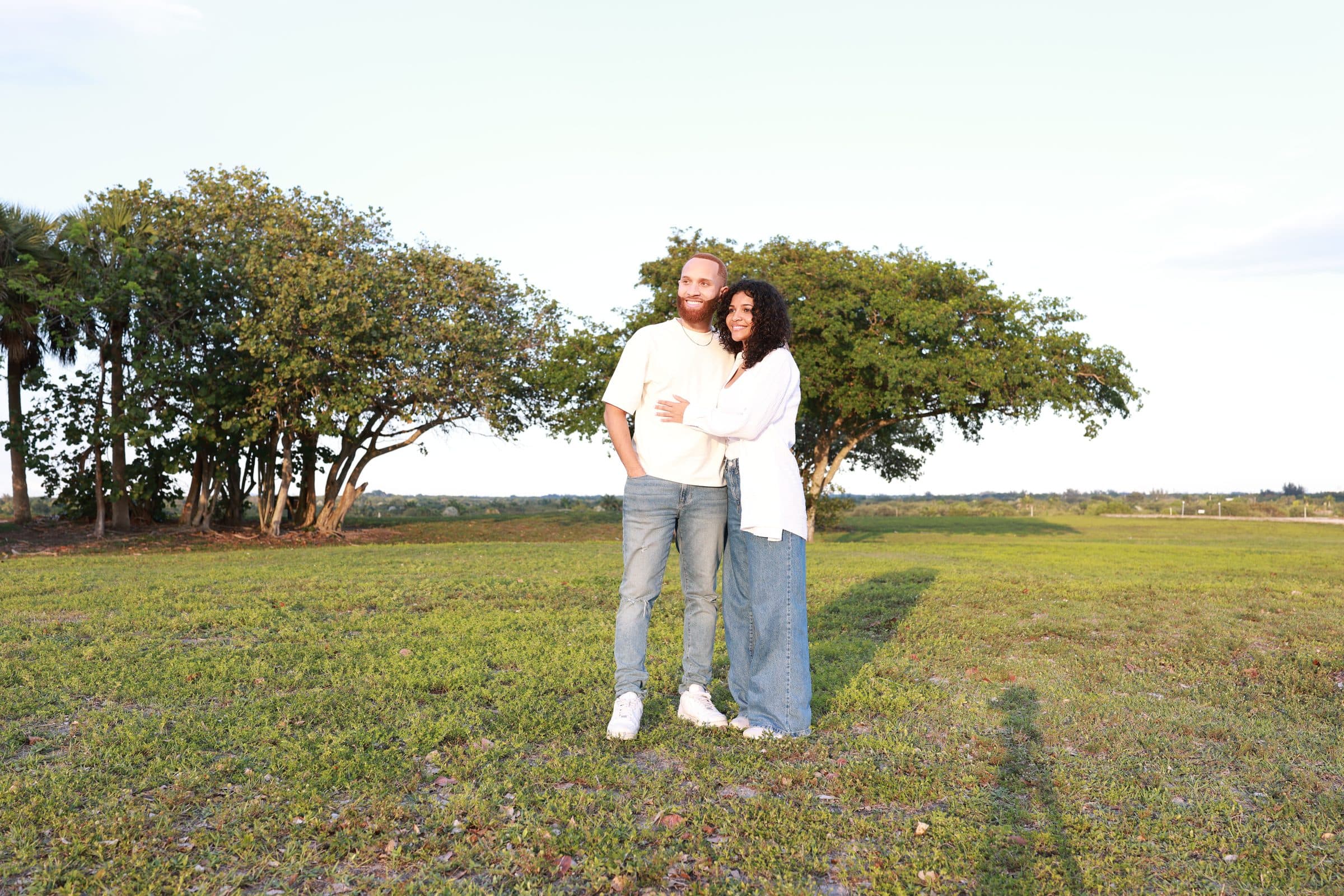 Ray and Alexia embracing beneath a large oak tree in a green field