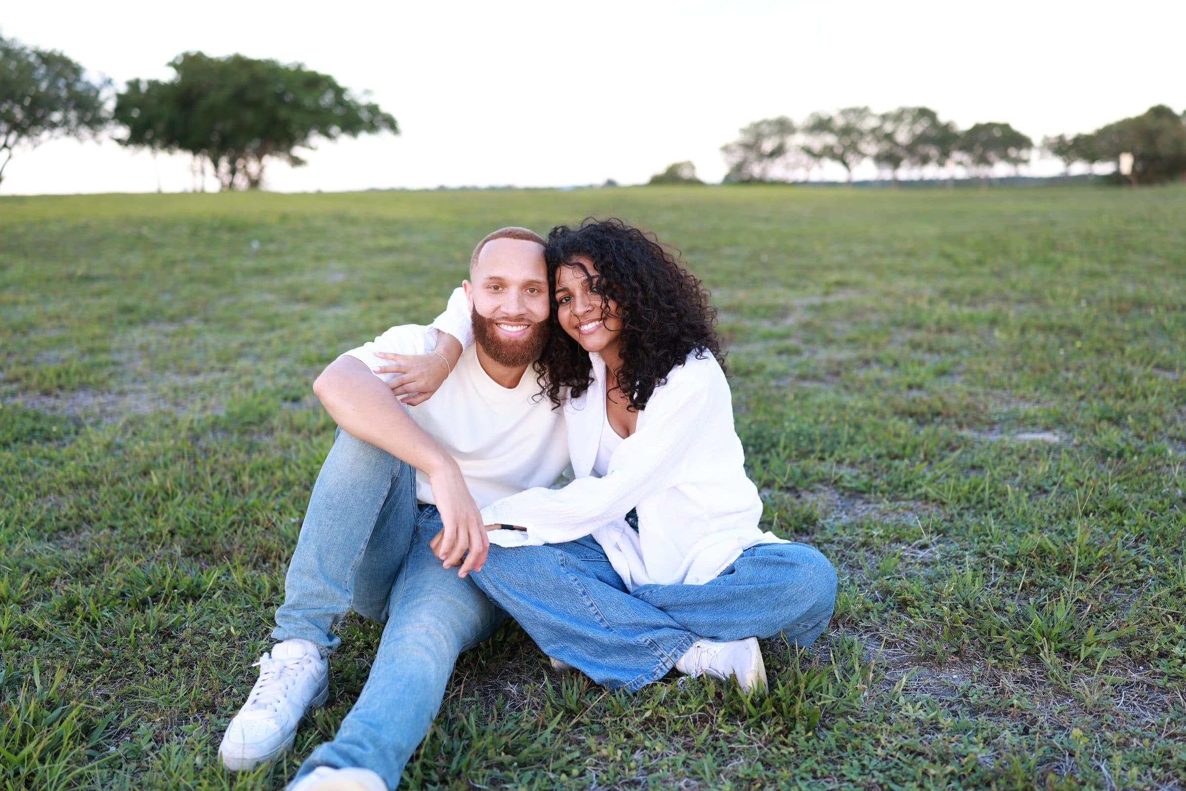 Ray and Alexia sitting close together in the grass, smiling
